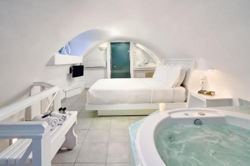 ein Schlafzimmer mit einer Badewanne, einem Bett und einem Bett sowie einer Badewanne in der Unterkunft Merovigliosso in Imerovigli