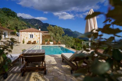 a pool with a table and chairs next to a house at Astrali Stone Villas in Paramythia