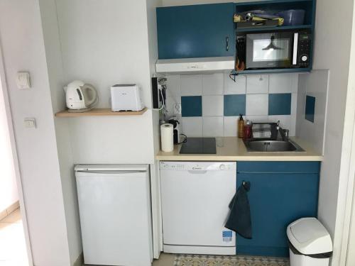 una pequeña cocina con electrodomésticos blancos y armarios azules en appartement studio, en Prayssac