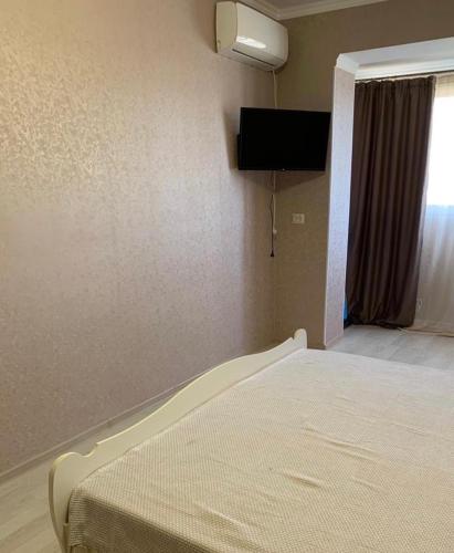 ein Schlafzimmer mit einem Bett und einem TV an der Wand in der Unterkunft Сдаётся 1-комнатная квартира в Гаграх in Gagra