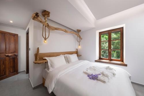 a bedroom with a bed with white sheets and a window at Palios Stathmos in Miléai