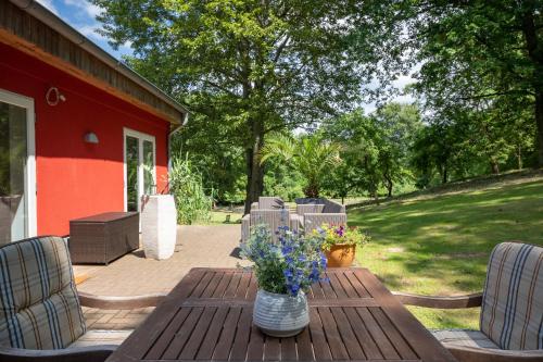 a wooden table with a vase of flowers on a patio at Seehotel Lindenhof in Lychen