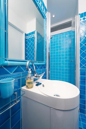 La salle de bains est pourvue de carrelage bleu, d'un lavabo et d'un miroir. dans l'établissement Palm Beach Amazing view, à Cannes