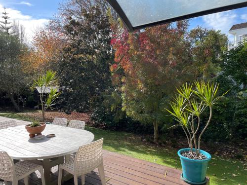 a patio with a table and chairs on a deck at Whitby Studio - Mairangi Bay Beach in Auckland