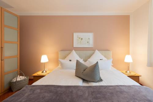 a bedroom with a large white bed with two lamps at Seehotel Lindenhof in Lychen