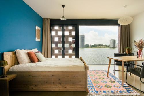 a bedroom with a bed and a table and a window at B&B Maasview in Rotterdam
