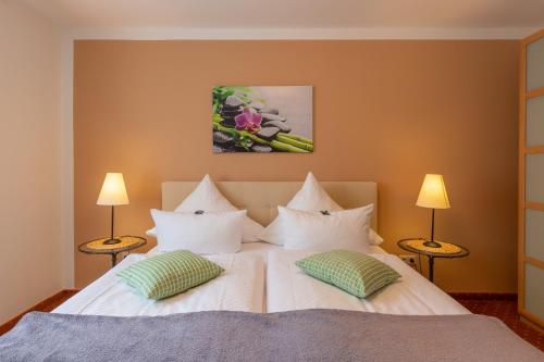 a bedroom with a white bed with two lamps at Seehotel Lindenhof in Lychen