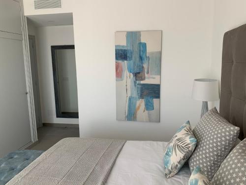 a bedroom with a bed and a painting on the wall at Apartamento en Playa Santo Tomas in Es Migjorn Gran