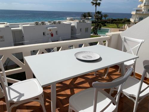 a white table and chairs on a balcony with the ocean at Apartamento en Playa Santo Tomas in Es Migjorn Gran