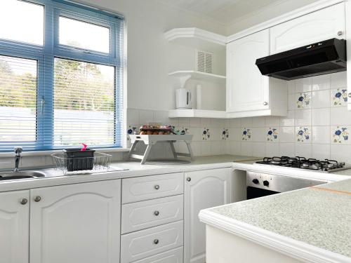 a white kitchen with white cabinets and a sink at SunnyVale Valley View Cottage in Gorran Haven
