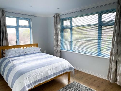 a bedroom with a bed and two windows at SunnyVale Valley View Cottage in Gorran Haven