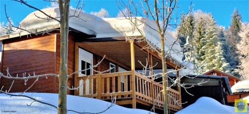 a log cabin with a deck in the snow at Camping Yoghi e Bubu in San Giacomo