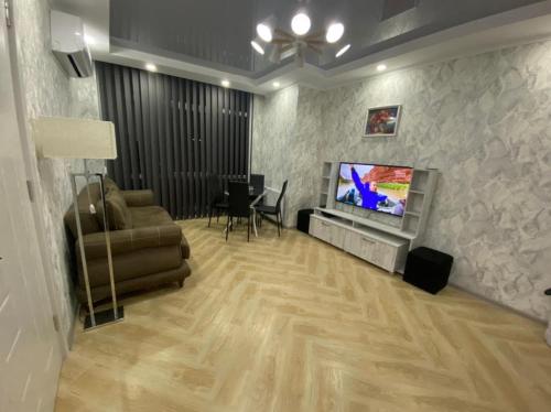 ein Wohnzimmer mit einem TV, einem Sofa und einem Tisch in der Unterkunft Panorama Black Sea in Batumi