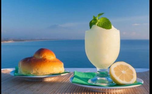 a drink in a glass next to a cake and a lemon at Casa Albigiò in Catania