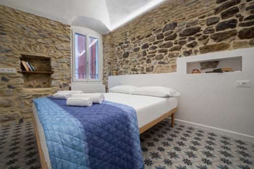 ein Schlafzimmer mit einem Bett und einer Steinmauer in der Unterkunft Insapria, Caressa de mä in Bordighera