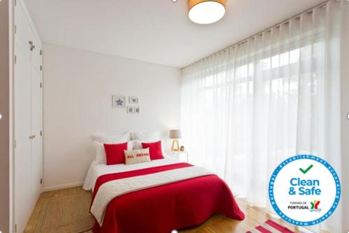 a bedroom with a red and white bed and a window at Sereia Garden Apartment in Coimbra