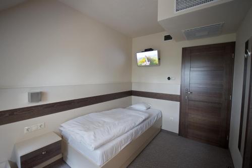 a small bedroom with a bed and a television at Napkelte Panzió in Napkor