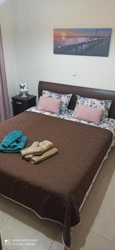 duże łóżko z brązową pościelą i różowymi poduszkami w obiekcie Fotini's Apartment w mieście Néa Péramos