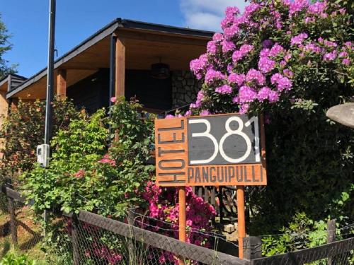 a sign in front of a house with flowers at Hotel 381 Panguipulli in Panguipulli