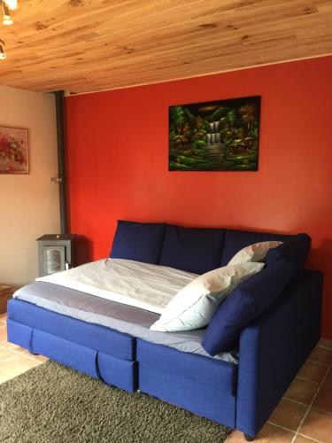 a bedroom with a blue bed with a red wall at Lac d'Annecy in Doussard