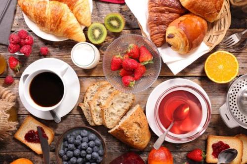 a wooden table topped with breakfast foods and a cup of coffee at CASA DI PIETRA MYKONOS in Klouvas