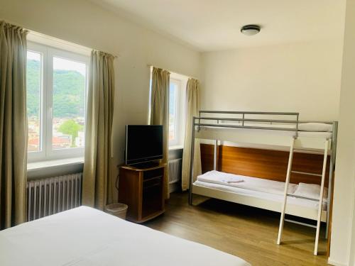 een slaapkamer met 2 stapelbedden en een televisie bij Hotel Gamper in Bellinzona