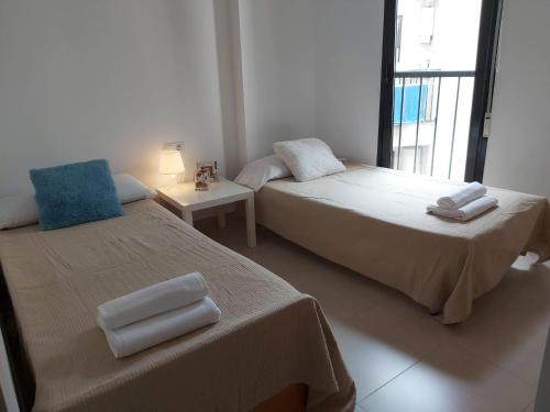 ein Schlafzimmer mit 2 Betten und einem Tisch mit einer Lampe in der Unterkunft ÁTICO PATACONA BEACH PLAYA in Valencia