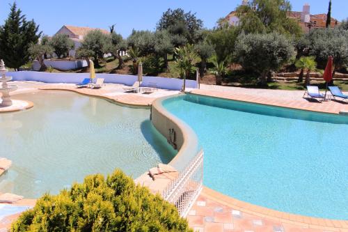 uma grande piscina com cadeiras num resort em Hotel de Charme Capela das Artes em Armação de Pêra