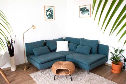 a blue couch in a living room with plants at Modernes 2-Zimmer-Apartment mit Balkon und Netflix in Jena