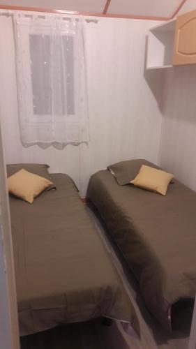 deux lits dans une petite pièce avec une fenêtre dans l'établissement Chalet les Hameaux du Perrier, à Lissac-sur-Couze