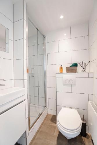 a white bathroom with a toilet and a shower at Papillon flat in Zandvoort