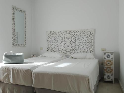a white bedroom with two beds and a mirror at Casas de Tauro in La Playa de Tauro