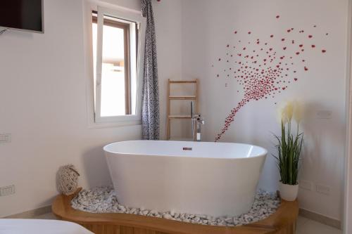 Una bañera blanca en un baño con ventana. en Intra Rooms, en Olbia