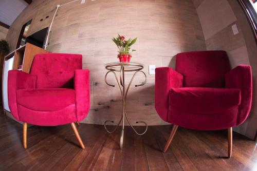 two red chairs and a table in a room at Hotel Ferrugem Eco Village in Garopaba