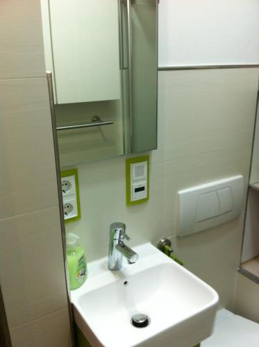 a bathroom with a white sink and a mirror at Joanna Apartment - MA Rheinau 3 in Mannheim