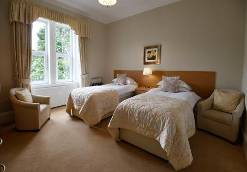 a bedroom with two beds and a chair and a window at Myrtle Bank Guest House in Fort William