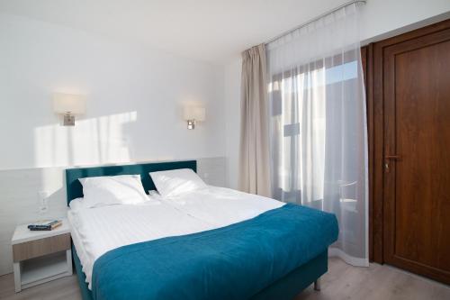 a bedroom with a bed with a blue and white blanket at Błękitne Wzgórze - Nowoczesne Pokoje Gościnne in Władysławowo