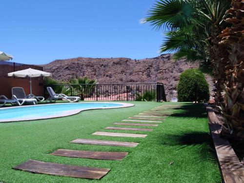 a backyard with a swimming pool and green grass at Casas de Tauro in La Playa de Tauro