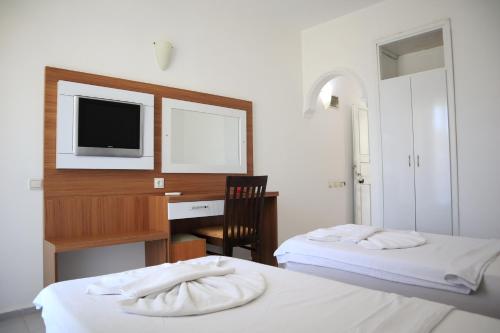 two beds in a room with a desk and a tv at Kleopatra smile hotel in Alanya