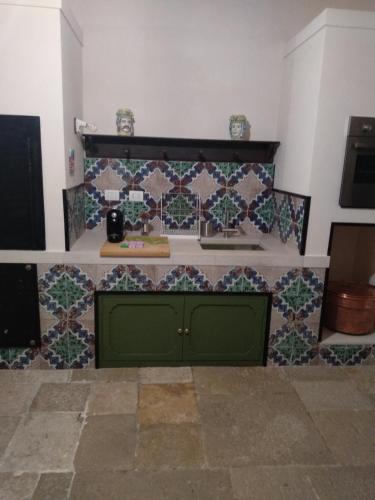a green cabinet in a room with tiles on the wall at Palazzo Rossi suite in Canosa di Puglia