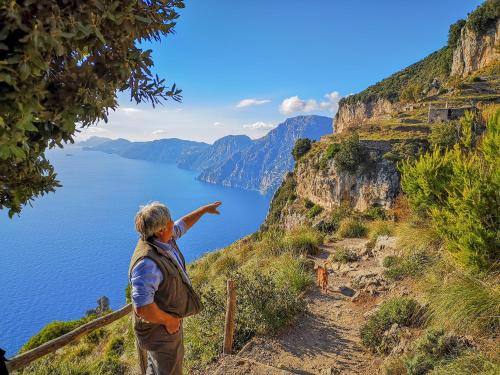 a man standing on a cliff looking at the ocean at Tenuta Novecento Bioagriturismo in Agerola
