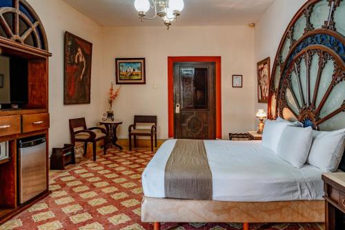 a hotel room with a large bed and a television at Casa del Balam Merida in Mérida