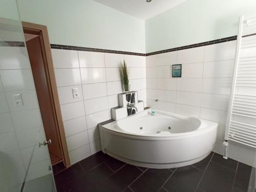 La salle de bains est pourvue d'une baignoire blanche et de carrelage blanc. dans l'établissement Ferienwohnung am Hopfengarten, à Illschwang