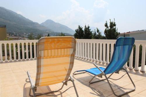 two chairs sitting on a balcony with mountains in the background at Vila AKI-KA in Sutomore