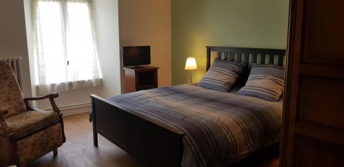 una camera con letto, sedia e televisore di Lodge-Sagne une ferme rénovée au cœur du Cantal à proximité de la station de ski du Lioran a Neussargues en Pinatelle