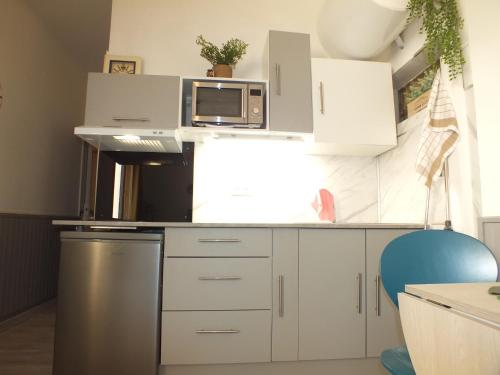 een keuken met witte kasten en een magnetron bij Studio Sirène à 20 m de la plage in Palavas-les-Flots
