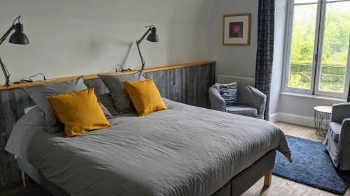 - une chambre avec un grand lit et des oreillers jaunes dans l'établissement La Maison Normande, à Saint-Cirgues-de-Jordanne