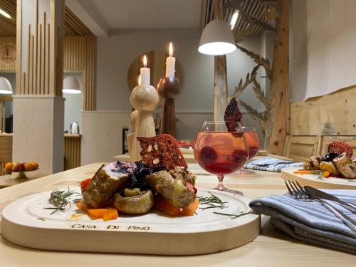 a plate of food on a table with a glass of wine at Casa di Pino EcoLodge Hotel in Žabljak