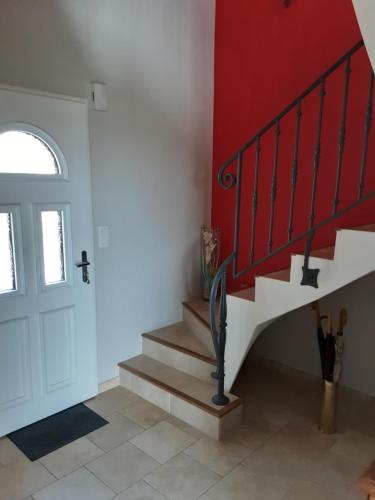 a staircase in a room with a red wall at Chambre d'hôtes de la Galie in Sainte-Marie-du-Mont