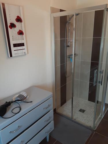 a shower with a glass door next to a dresser at Chambre d'hôtes de la Galie in Sainte-Marie-du-Mont